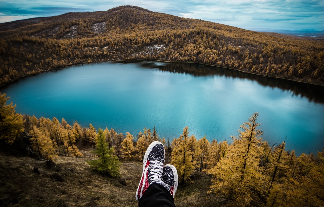 POV photo of mountains and a lake with person's shoes in the frame, around the world flights, RTW